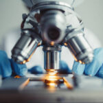 Close up of examining of test sample under the microscope in laboratory.